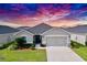 Charming single-story home boasts a well-manicured lawn and an attached two-car garage with a dramatic sunset sky in the background at 561 Vittorio Dr, Winter Haven, FL 33884