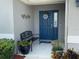Welcoming front porch with a blue front door, adorned with potted plants and bench, creates a warm and inviting entryway at 561 Vittorio Dr, Winter Haven, FL 33884