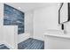Modern bathroom features blue tiled floors and wall accent, white fixtures, and a sleek vanity sink at 650 Mesilla Dr, Kissimmee, FL 34758