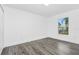 Bright bedroom featuring gray wood floors, white walls, and a window offering a view of the yard at 650 Mesilla Dr, Kissimmee, FL 34758