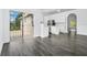 Open living space with gray wood floors, sliding glass door, and a kitchen with white cabinets at 650 Mesilla Dr, Kissimmee, FL 34758
