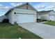 A bright white two car garage with a concrete driveway and manicured lawn at 6783 Grace Hammock Rd, Harmony, FL 34773