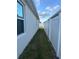Side yard showing new white fence and a small grass area at 6783 Grace Hammock Rd, Harmony, FL 34773