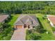 Beautiful aerial view of home with tile roof, brick driveway, lush landscaping, and green space at 819 San Raphael St, Kissimmee, FL 34759