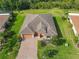Stunning aerial view of home with tile roof, brick driveway, lush landscaping, and views of green space and trees at 819 San Raphael St, Kissimmee, FL 34759