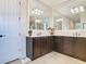 Bathroom area includes a double sink vanity with dark cabinetry, large mirrors, and ample lighting fixtures at 819 San Raphael St, Kissimmee, FL 34759