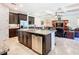An open kitchen with stainless steel appliances, a large island, and stylish brown cabinets leads into the living area at 819 San Raphael St, Kissimmee, FL 34759