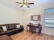This home office features a cozy couch, a decorative mirror, a ceiling fan and a window with blinds at 819 San Raphael St, Kissimmee, FL 34759