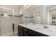 Modern bathroom with dual sinks, dark wood cabinets, and a glass-enclosed shower featuring decorative tile at 9038 Pelican Cove Trce, Kissimmee, FL 34747