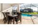 Inviting outdoor dining area with wicker seating, adjacent to a refreshing pool and spa at 9038 Pelican Cove Trce, Kissimmee, FL 34747
