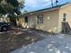 Side view of a yellow home featuring a modest yard with a concrete walkway leading to the front door at 98 Orange Park Blvd, Lake Wales, FL 33898