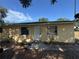 Charming yellow home with a white front door, brightened by the blue sky and dappled sunlight at 98 Orange Park Blvd, Lake Wales, FL 33898