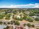 Aerial view of a community with lush greenery, roads, and clear blue skies on a sunny day at 12539 Orangewood Ct, Tavares, FL 32778