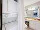 Bathroom features a vanity, toilet, mirror, and an adjacent laundry area with a stacked washer/dryer at 12539 Orangewood Ct, Tavares, FL 32778