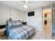Bedroom featuring a ceiling fan, mounted television, neutral tones, and an adjacent bathroom at 12539 Orangewood Ct, Tavares, FL 32778