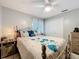 Cozy bedroom with a floral bedspread, ceiling fan, and natural light filtering through the window at 12539 Orangewood Ct, Tavares, FL 32778