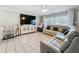 Spacious living room featuring a white leather sectional, tile flooring, and a large TV with entertainment center at 12539 Orangewood Ct, Tavares, FL 32778
