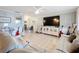 Open living room with white leather couches, tile flooring, and modern white entertainment center at 12539 Orangewood Ct, Tavares, FL 32778