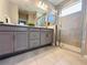 Bathroom featuring double sinks, gray cabinets, and a frameless glass shower at 1321 Yorkdale Rd, Davenport, FL 33837