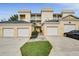View of condo building with multiple garage spaces, manicured landscaping, and ample parking at 1501 Northern Harrier Way # 101, Kissimmee, FL 34747