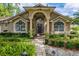 Inviting front entrance featuring an arched doorway, columns, and lush landscaping at 154 Academy Oaks Pl, Altamonte Springs, FL 32714