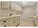 Laundry room featuring tile floors, countertops, and cabinets, with an adjacent folding rack and utility sink at 154 Academy Oaks Pl, Altamonte Springs, FL 32714