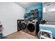 Modern laundry room featuring gray washer/dryer, shelving and a blue accent wall at 1823 Ashton E Dr, St Cloud, FL 34771