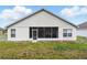 Back exterior of a single story home with a screened lanai, grassy lawn, and blue skies at 1823 Ashton E Dr, St Cloud, FL 34771