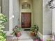 Inviting front entrance with a decorative door, arched window, and colorful potted plants at 2365 Paulette Dr, Haines City, FL 33844