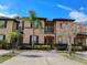 Inviting exterior of a tan townhouse featuring a balcony, palm trees, and well-maintained landscaping at 247 Verona Ave, Davenport, FL 33897