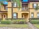 Townhome exterior with yellow stucco, a palm tree, a brick walkway, and shutters at 247 Verona Ave, Davenport, FL 33897