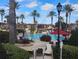 Resort-style pool area with palm trees, comfortable lounge chairs, and vibrant red umbrellas at 247 Verona Ave, Davenport, FL 33897