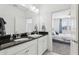 Bathroom featuring a double sink with granite countertop, white cabinets, and view to main bedroom at 256 Captiva Dr, Davenport, FL 33896