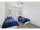 Bright bedroom featuring two twin beds, ceiling fan, natural lighting, and neutral color scheme at 256 Captiva Dr, Davenport, FL 33896