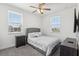Cozy bedroom with a gray upholstered bed, ceiling fan, and natural light from two windows at 256 Captiva Dr, Davenport, FL 33896