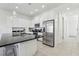 Modern kitchen with white cabinets, stainless steel refrigerator and black countertops with tile floors at 256 Captiva Dr, Davenport, FL 33896