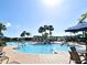 Wonderful community pool with blue umbrellas, resort style pool deck, lounge chairs, and mature palm trees at 2778 Almaton Loop # 403, Kissimmee, FL 34747