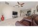 Cozy living room with a brown leather couch, large TV, ceiling fan, and tiled floors at 3890 Prairie Reserve Blvd, Orlando, FL 32824