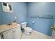 Powder room with blue walls, white fixtures, and tiled floor offers a clean and functional space at 4091 Lippman Rd, St Cloud, FL 34772