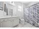 Well-lit bathroom with a modern vanity, mirror, tiled floors, and a stylish blue and white wave-patterned shower curtain at 438 Marcello Blvd, Kissimmee, FL 34746
