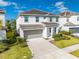 Two-story home featuring a neutral color palette, a two-car garage, and landscaped front yard at 438 Marcello Blvd, Kissimmee, FL 34746