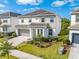 Two-story home featuring a neutral color palette, a two-car garage, and lush landscaping at 438 Marcello Blvd, Kissimmee, FL 34746