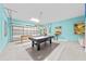 Spacious game room with a pool table, foosball table, a roll up garage door and brightly colored walls at 438 Marcello Blvd, Kissimmee, FL 34746