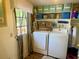 Functional laundry room with washer, dryer, shelving, and a door to the outside at 455 E Palmetto Ave, Longwood, FL 32750