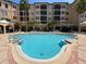 Community pool with ample lounge seating, palm trees, and a multi-story condo building in the background at 501 Mirasol Cir # 203, Celebration, FL 34747