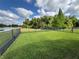 Large backyard features lush grass, a sleek black fence, and peaceful lake views beyond at 650 Portofino Drive, Poinciana, FL 34759