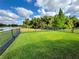 Expansive backyard featuring lush green grass, an iron fence and tranquil lake views at 650 Portofino Drive, Poinciana, FL 34759