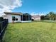 Spacious backyard featuring lush green grass, black metal fence, and a screened-in patio area for outdoor entertaining at 650 Portofino Drive, Poinciana, FL 34759