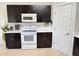Well-equipped kitchen with dark wood cabinetry, white appliances, and bright countertops at 650 Portofino Drive, Poinciana, FL 34759