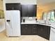 Stylish kitchen boasting dark wood cabinets, white counters, and stainless steel refrigerator at 650 Portofino Drive, Poinciana, FL 34759